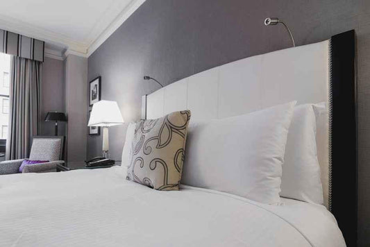 Close-up of a hotel bed with decorative pillows and a modern lamp in a stylish room.