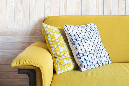 Yellow couch with two decorative pillows